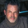 A middle-aged man with salt-and-pepper hair and a warm smile looks directly into the camera lens.