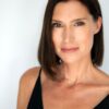 A professional headshot of a brunette woman with a friendly, natural expression against a plain white background.