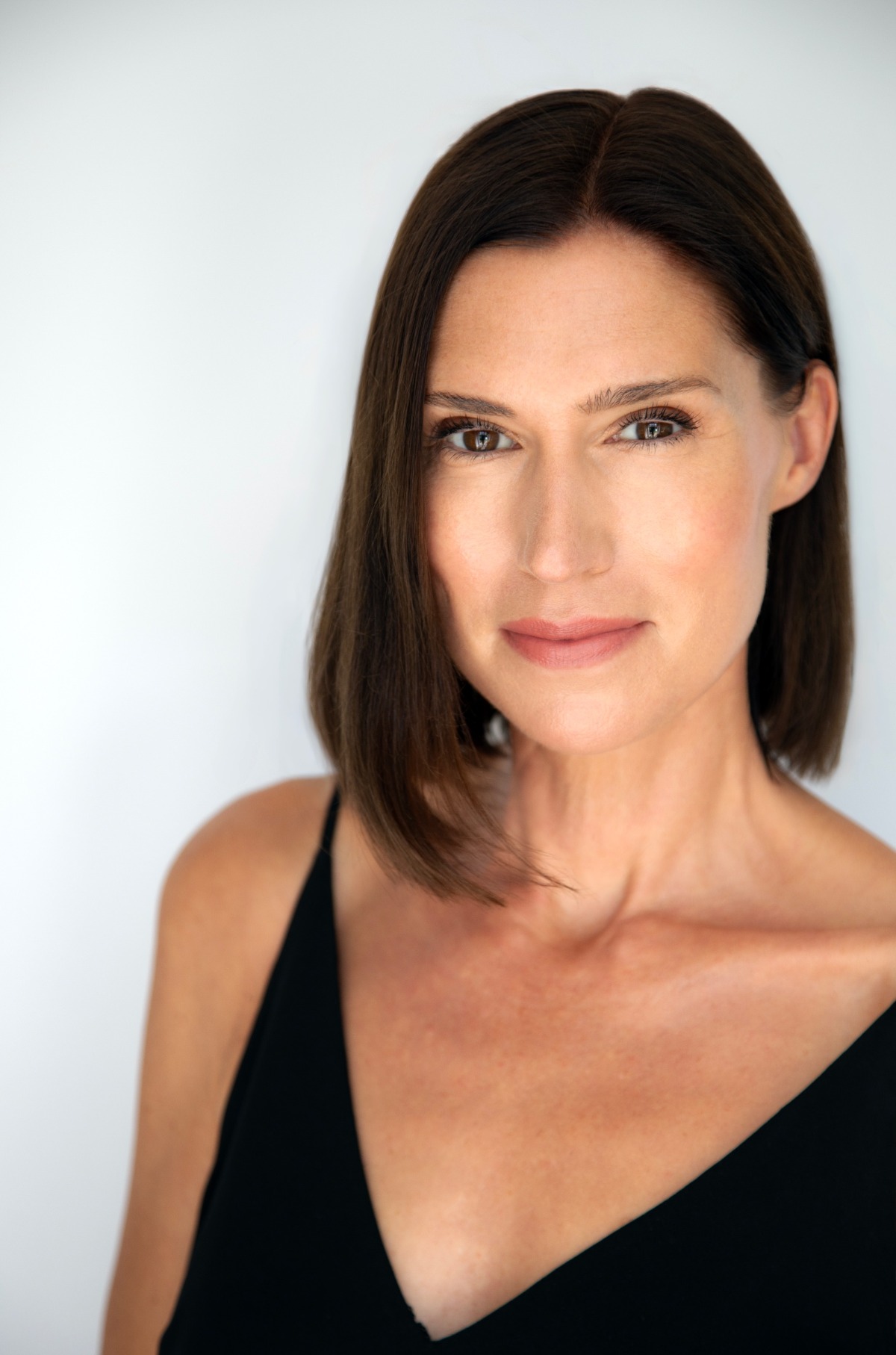 A professional headshot of a brunette woman with a friendly, natural expression against a plain white background.
