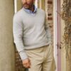 A handsome man in a sweater and shorts leans against a pillar, capturing a relaxed, approachable lifestyle vibe.
