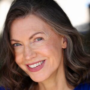 A warm and friendly mature woman with a bright smile posing for a professional commercial headshot portrait.