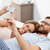 Young couple lying on bed using mobile phone