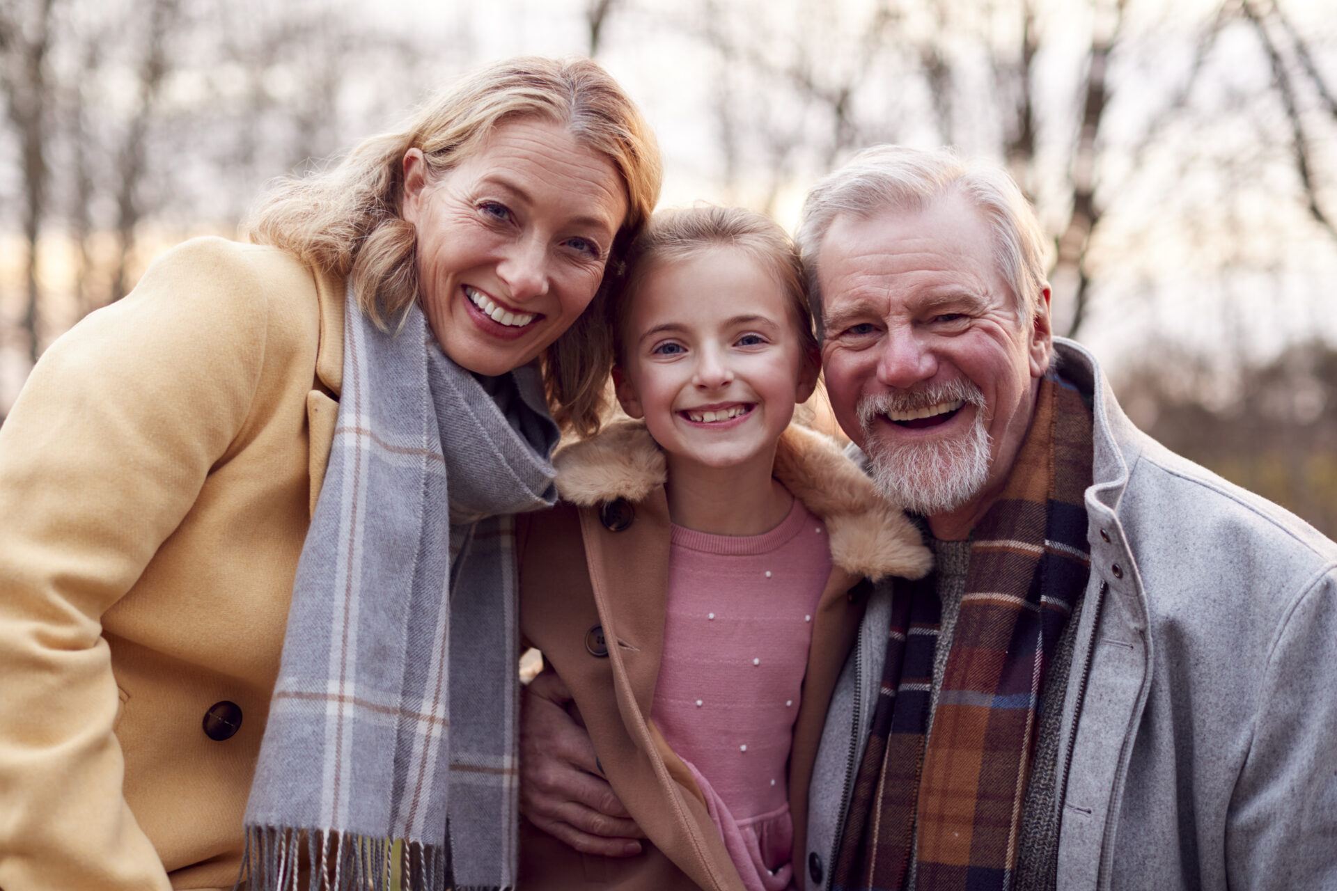 Portrait Of Grandparents With Granddaughter Outside Walking Through Winter Countryside