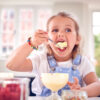 Young Girl In Kitchen Eating Ice Cream Dessert With Spoon
