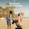A young family enjoys a sunny walk on the beach with a pram for a commercial advertisement.