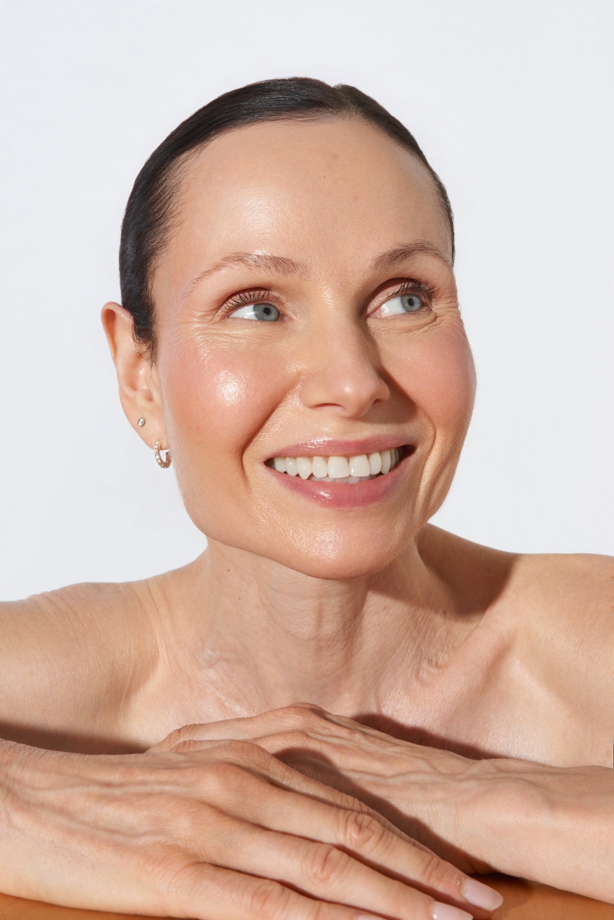 sasha-finn-5 A radiant middle-aged woman with natural skin texture smiles brightly in a clean, high-key studio setting.