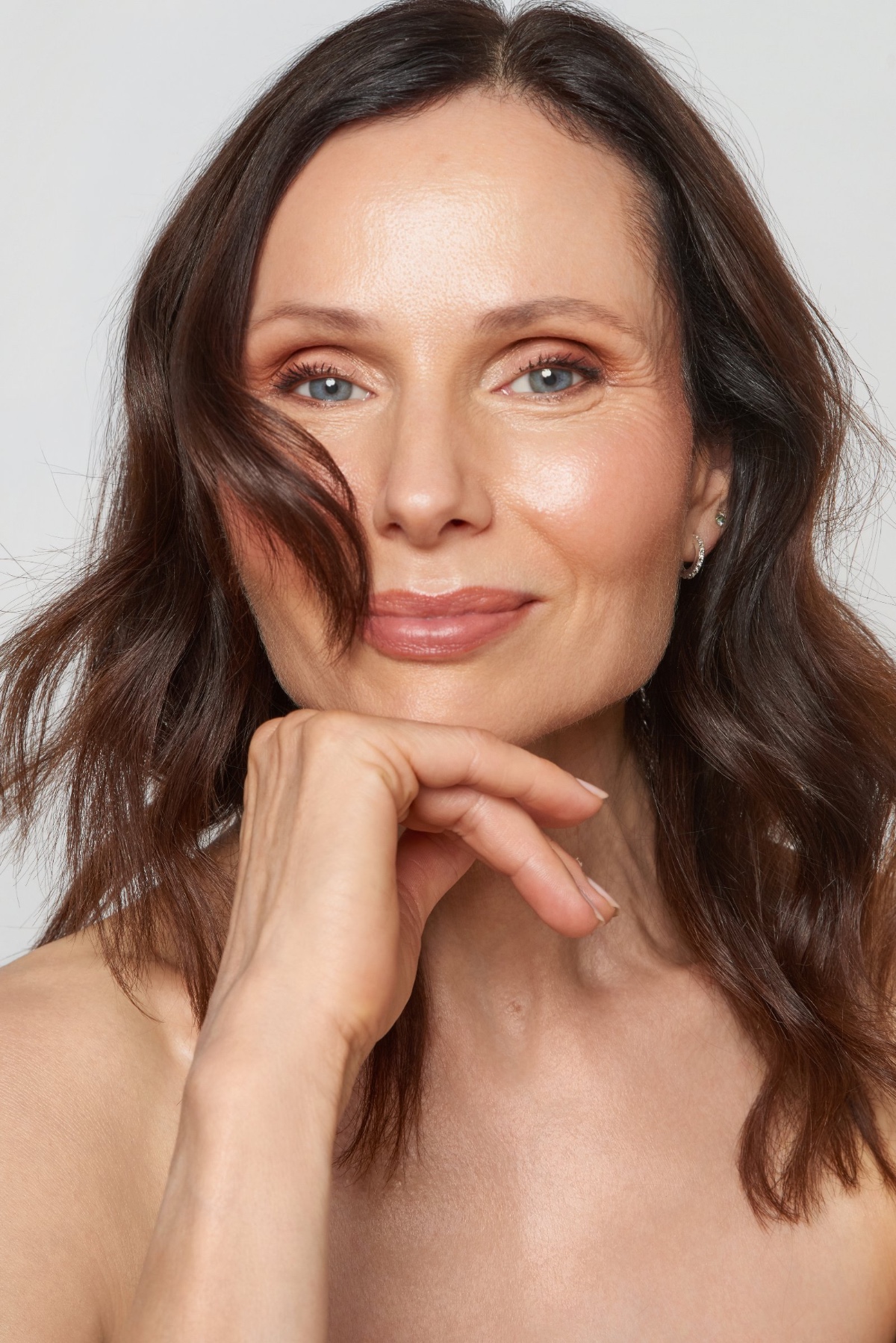sasha-finn-7 A smiling brunette woman with natural makeup poses for a bright and professional commercial headshot against grey.