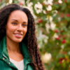 Smiling Young Woman Wearing Coat Standing Outside In Autumn Or Winter Countryside