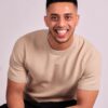 abdul-wadid-1 A man with a kind smile wears a beige sweater against a clean, bright studio portrait backdrop.