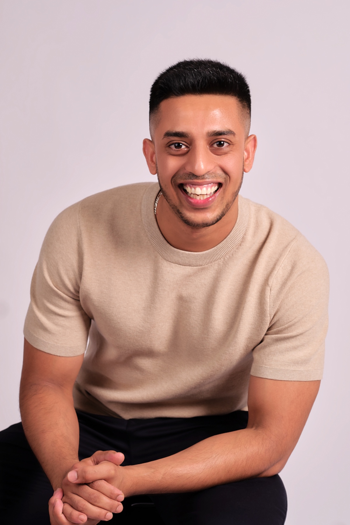 abdul-wadid-1 A man with a kind smile wears a beige sweater against a clean, bright studio portrait backdrop.