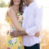 A happy diverse couple embraces in a bright, sun-drenched golden wheat field during a summer day.