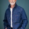 peter-williams-1 A silver-haired middle-aged man with a beard wearing a denim jacket poses against a teal studio background.