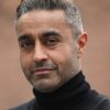 mohan-randhawa-6 A portrait of a middle-aged man with salt and pepper hair, wearing a black turtleneck jumper outdoors.