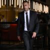 mohan-randhawa-11 A man in a sharp black suit walking through a contemporary bar setting with warm interior lighting.