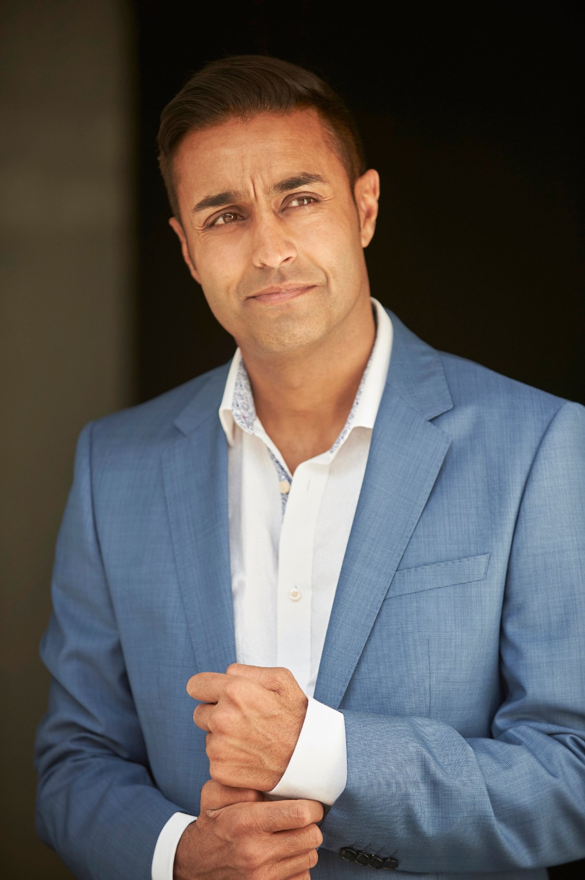 A well-dressed man in a blue suit looks away thoughtfully in this professional commercial headshot portrait.