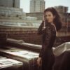 helena-antonio-7 A dark-haired woman in a black lace top poses on a city rooftop during a summer day.