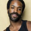 nathan-lobban-5 A warm portrait of a man with a beard, wearing a black tank top, against a golden background.
