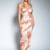A blonde woman posing in a vibrant, marble-patterned floor-length dress against a neutral grey studio backdrop.