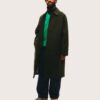 nathan-lobban-10 A stylish bearded man stands against a plain background, wearing a green coat, cap, and blue jeans.