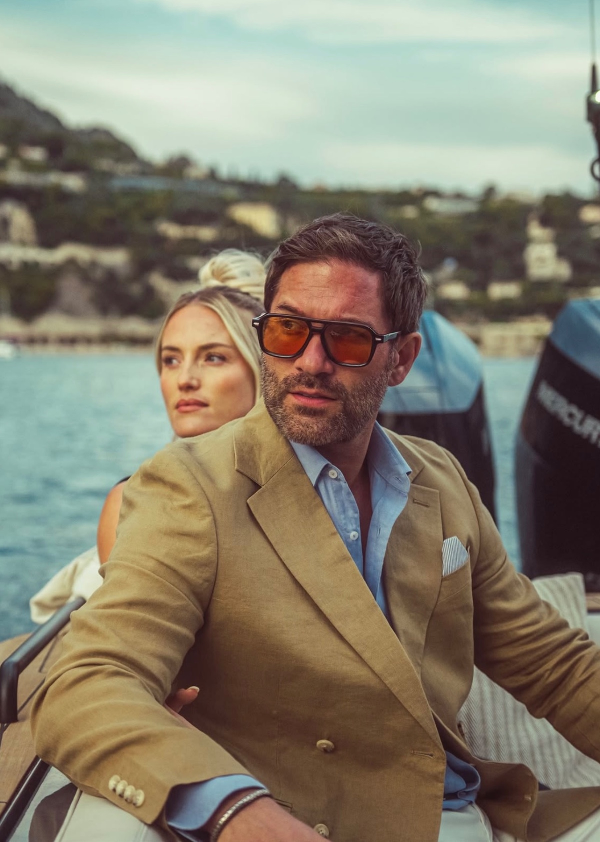 A stylish couple relaxes on a boat while enjoying a sunny day out on the water.