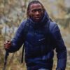 tobi-thomas-7 A fit male model wearing a dark puffer jacket hiking outdoors with walking poles in a forest.