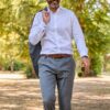 A smiling middle-aged man in formal business attire walks through a park with a friendly, approachable expression.