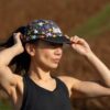 A female runner adjusts her star-patterned cap while exercising outdoors in the warm afternoon sunlight.